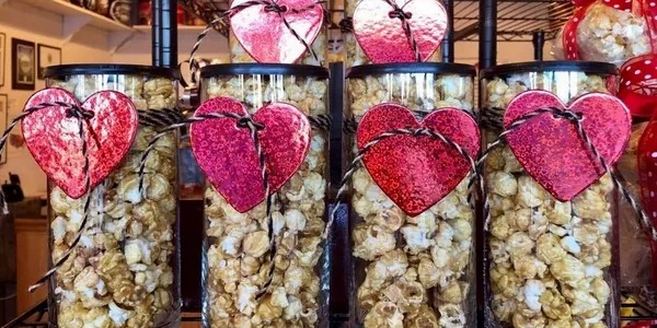 A couple of jars filled with popcorn and some hearts.