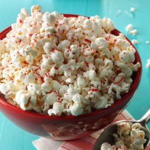 A bowl of popcorn with candy canes in it.